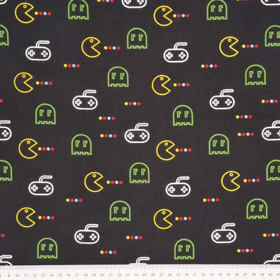 A video game design in green and yellow printed on a black polycotton fabric with a cm ruler at the bottom