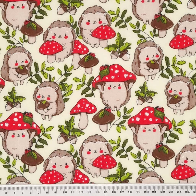 Cute hedgehogs and toadstools with ladybirds are printed on a cream polycotton fabric with a cm ruler