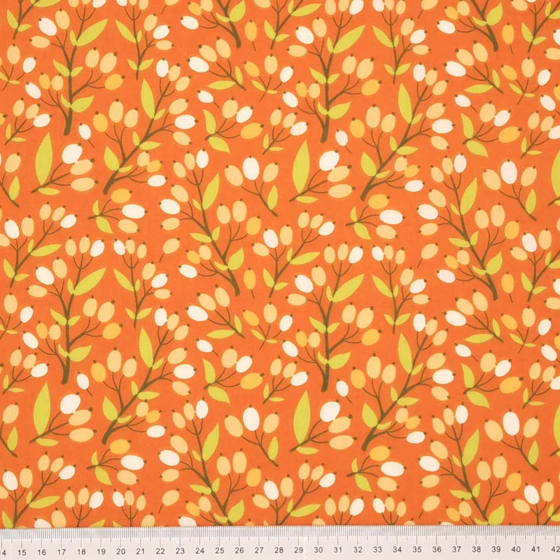 A floral design with berries printed on a rust coloured polycotton fabric with a cm ruler at the bottom