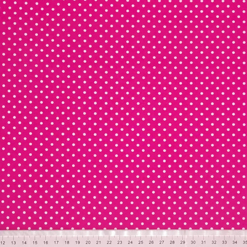 A mini white spot design printed on a cerise Rose and Hubble cotton poplin fabric with a cm ruler at the bottom
