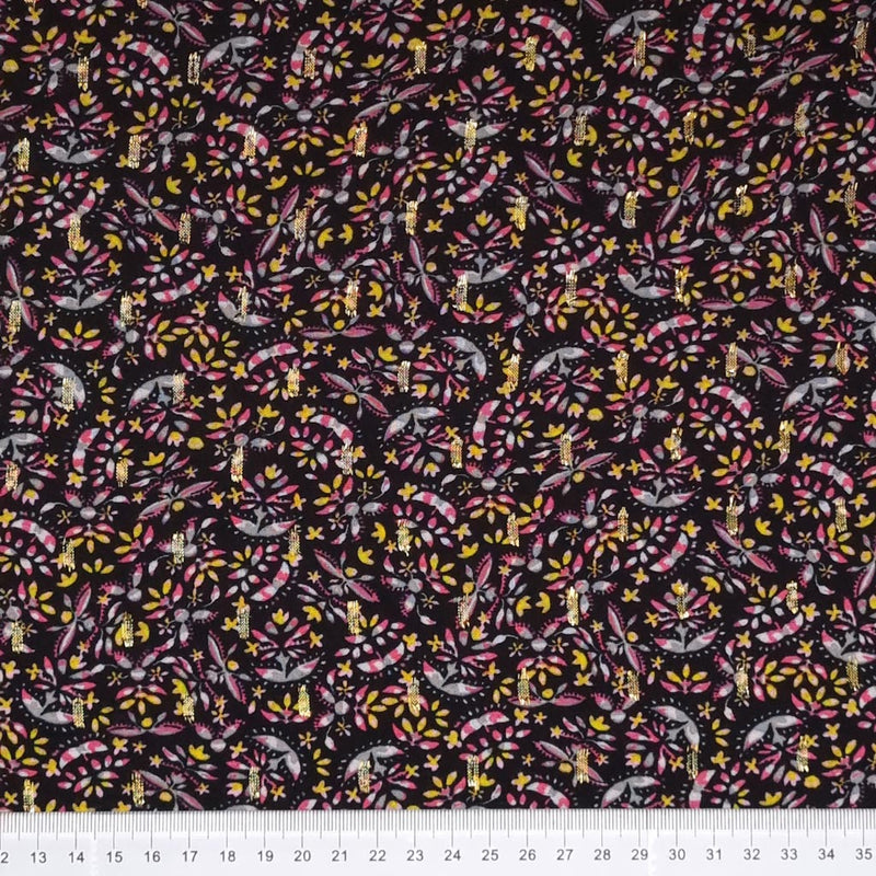 A ditsy floral design with golden lurex printed on a black viscose fabric with a cm ruler at the bottom