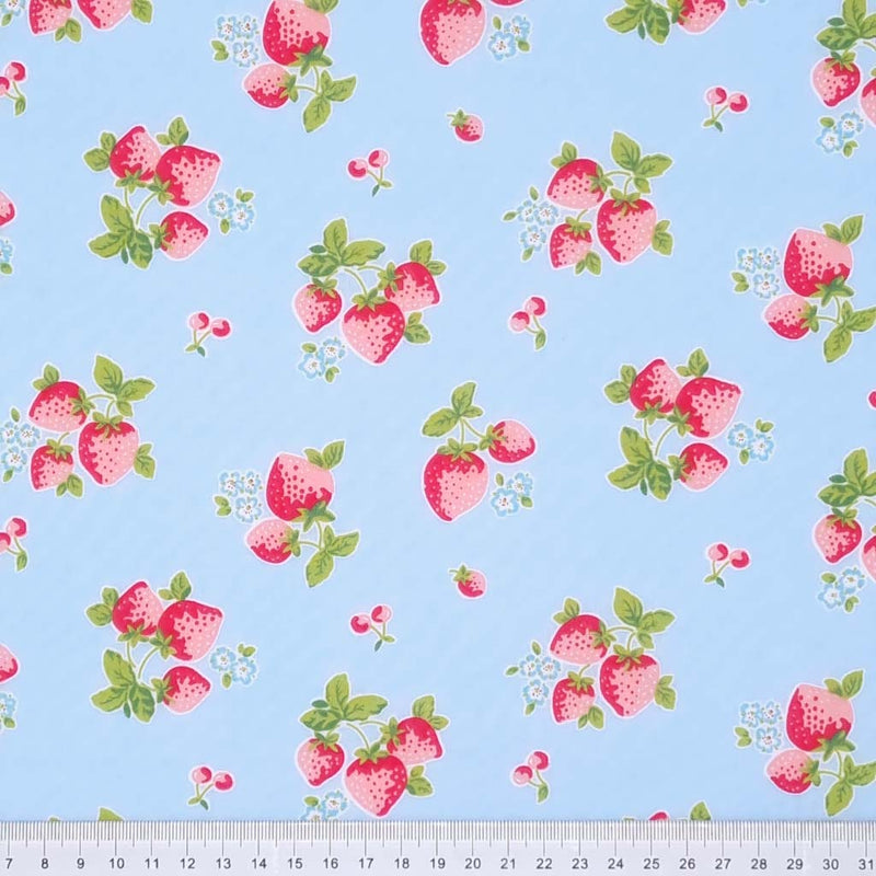 Red strawberries are printed on a sky blue polycotton fabric with a cm ruler at the bottom