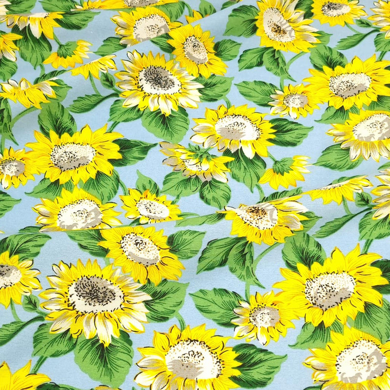 A vibrant sunflower print on a blue rayon mix fabric.