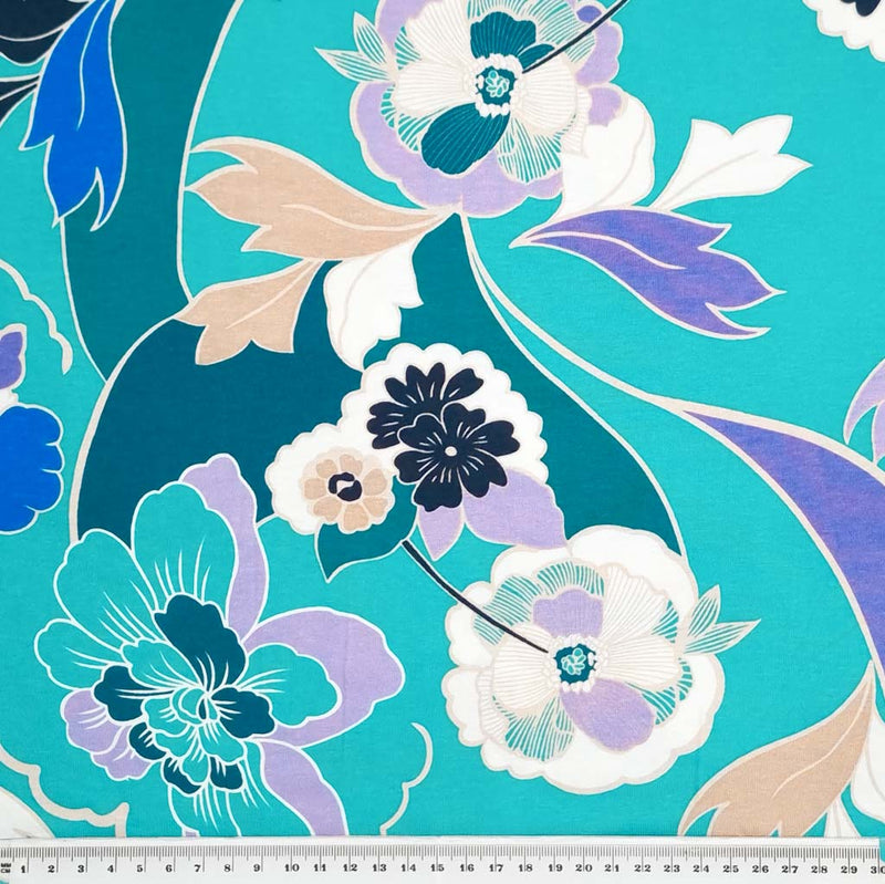 A beautiful lilac, emerald and blue floral print on a turquoise viscose jersey fabric with a cm ruler