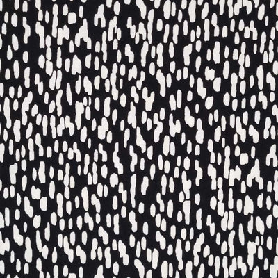 White falling spots are printed on a black viscose jersey fabric