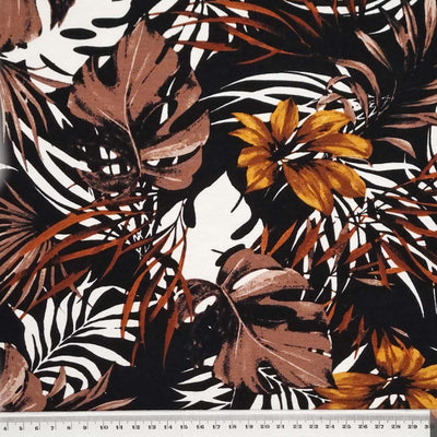 A beautiful golden floral print with leaves and tropical flowers on a viscose jersey fabric with a cm ruler