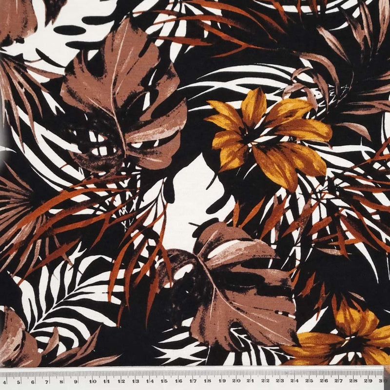 A beautiful golden floral print with leaves and tropical flowers on a viscose jersey fabric with a cm ruler